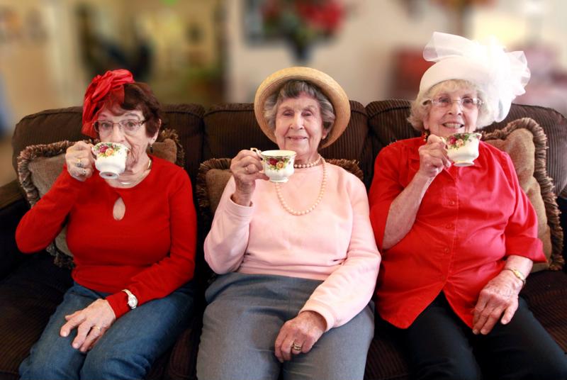 Three seniors sitting on couch at Edgewood drinking tea.