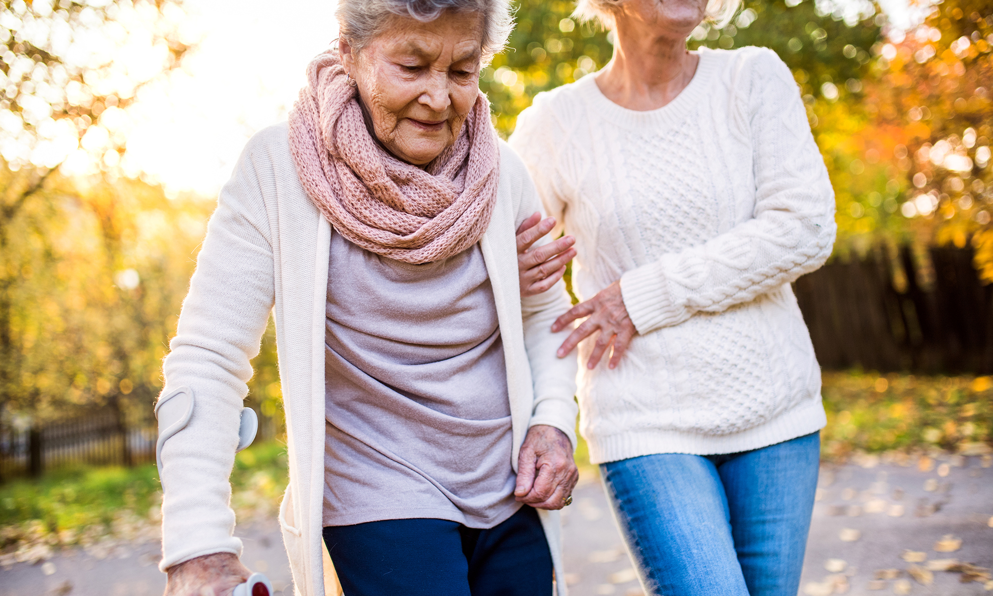 Female caregiver helping her senior loved one walk safely.