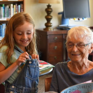 Senior and female child looking at a book inside of a library