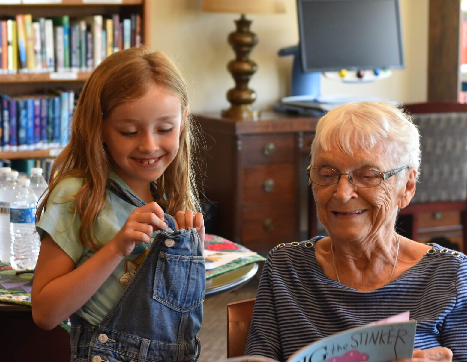 Senior and female child looking at a book inside of a library